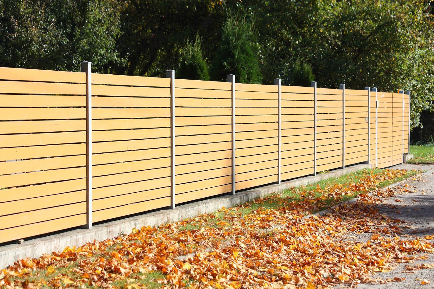A beautiful horizontal fence with fall leaves on the ground - if you want a horizontal front yard fence in Schaumburg, IL contact 76 FENCE.
